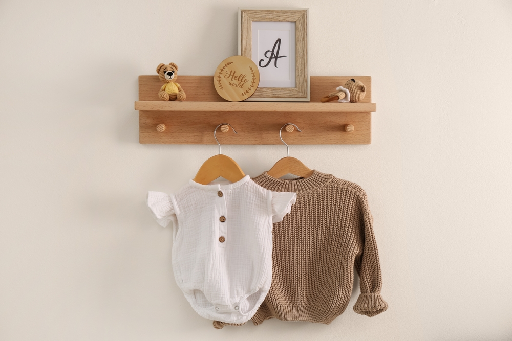 Petite étagère en bois avec des vêtements bébé fixée au mur