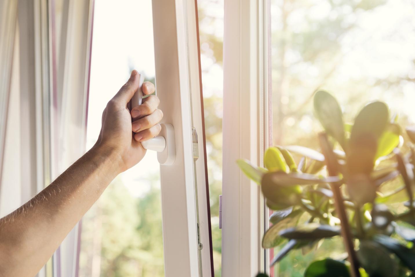 une personne ouvre une fenêtre pour ventiler et évacuer l'air vicier