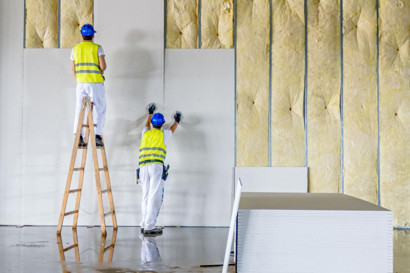 Une équipe de plaquiste assemble des plaques de plâtre et de l'isolation murale.